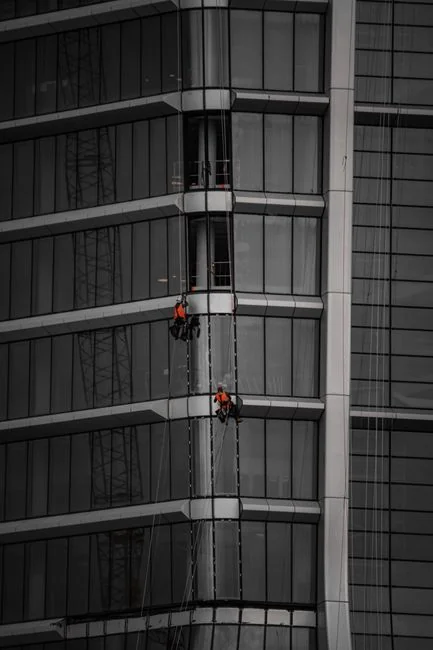 High-rise glass facade with suspended platform for window cleaning.